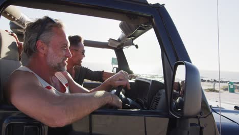 Glückliches-Kaukasisches-Schwules-Männliches-Paar-Im-Auto,-Das-Die-Aussicht-Bewundert-Und-An-Einem-Sonnigen-Tag-Am-Strand-Zeigt