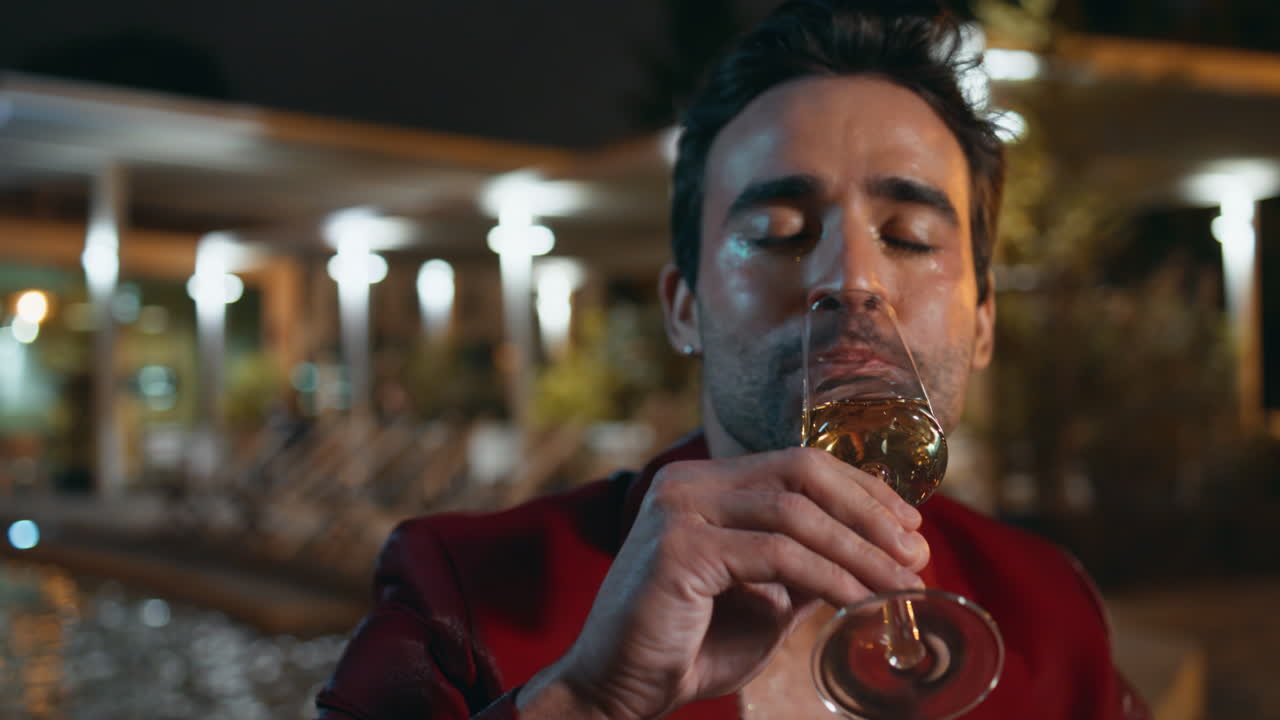 un caballero elegante bebiendo champán en una fiesta nocturna de cerca.