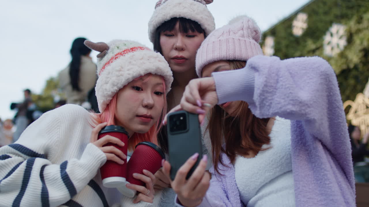 Three women taking a selfie with winter hats and coffee cups