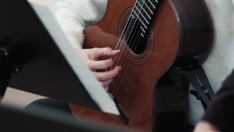 detalle de una guitarra clásica y manos femeninas tocando en ella