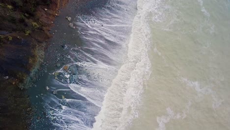 Aerial-shot-of-Big-Sur-beach-waves-flying-towards-an-RV-parked-off-foggy-road-perched-on-huge-cliffs-in-California