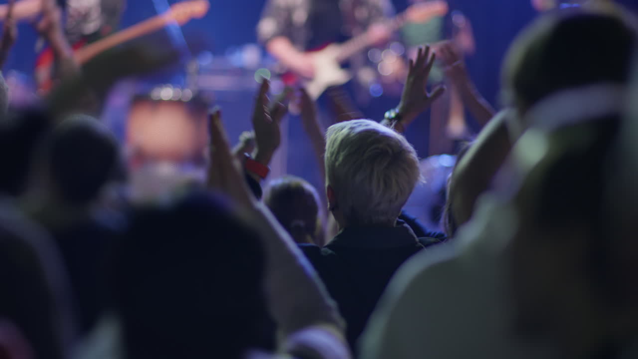 Fan klatscht bei Live-Konzert mit verschwommener Bühne im Hintergrund