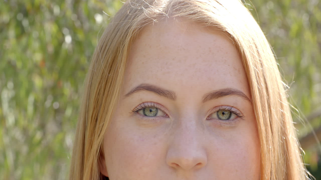 Close-up of woman with green eyes and blonde hair, looking directly at camera