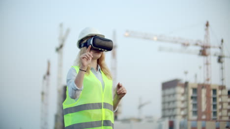 Porträt-Einer-Kranführerin,-Die-Eine-Baustelle-Mit-Einer-Virtual-Reality-Brille-Bedient.-Frau-Im-Baugewerbe.-Managerin-Verwaltet-Den-Fortschritt-Und-Die-Planung-Von-Gebäuden-Mithilfe-Von-Gesten-Bei-Sonnenuntergang