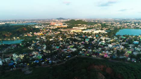 Drone-shot-panning-a-city-from-above-showing-water-bodies,-houses-and-roads