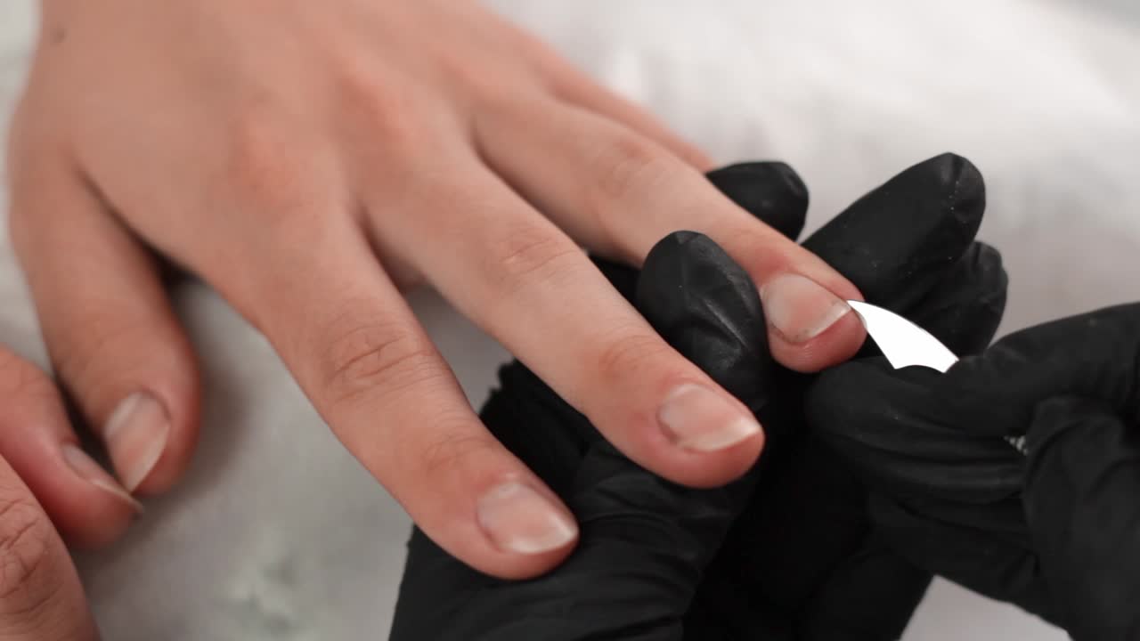 esteticista usando una cuchilla afilada para limpiar debajo de las uñas de un cliente