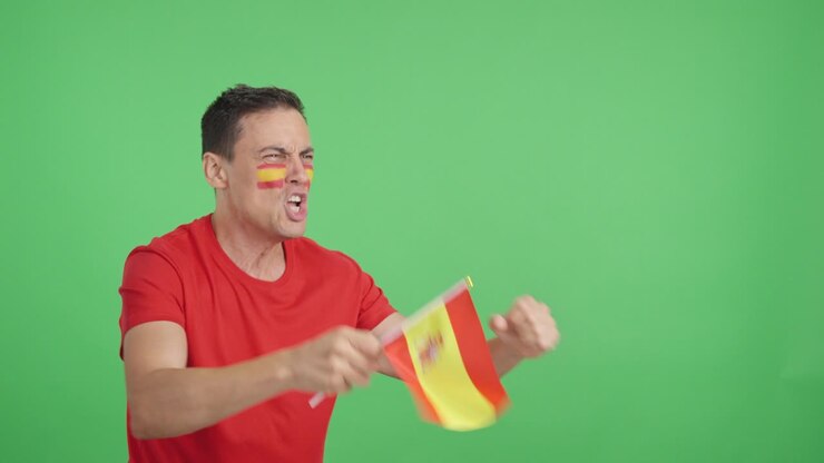 Spanish supporter screaming and waving a national flag looking away