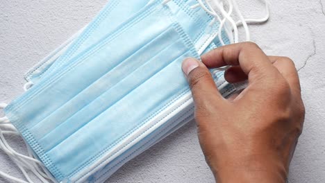 a person holding a stack of blue surgical face masks