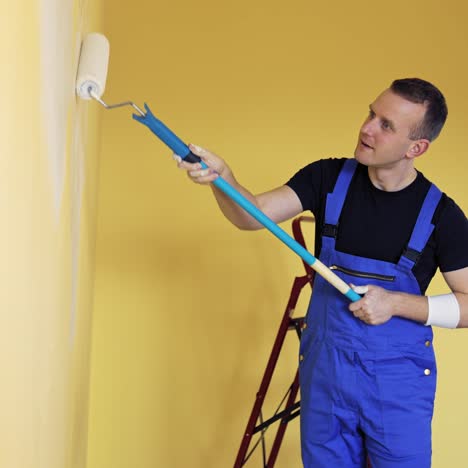 man decorating room in new home. man painting wall during home decoration with roller brush