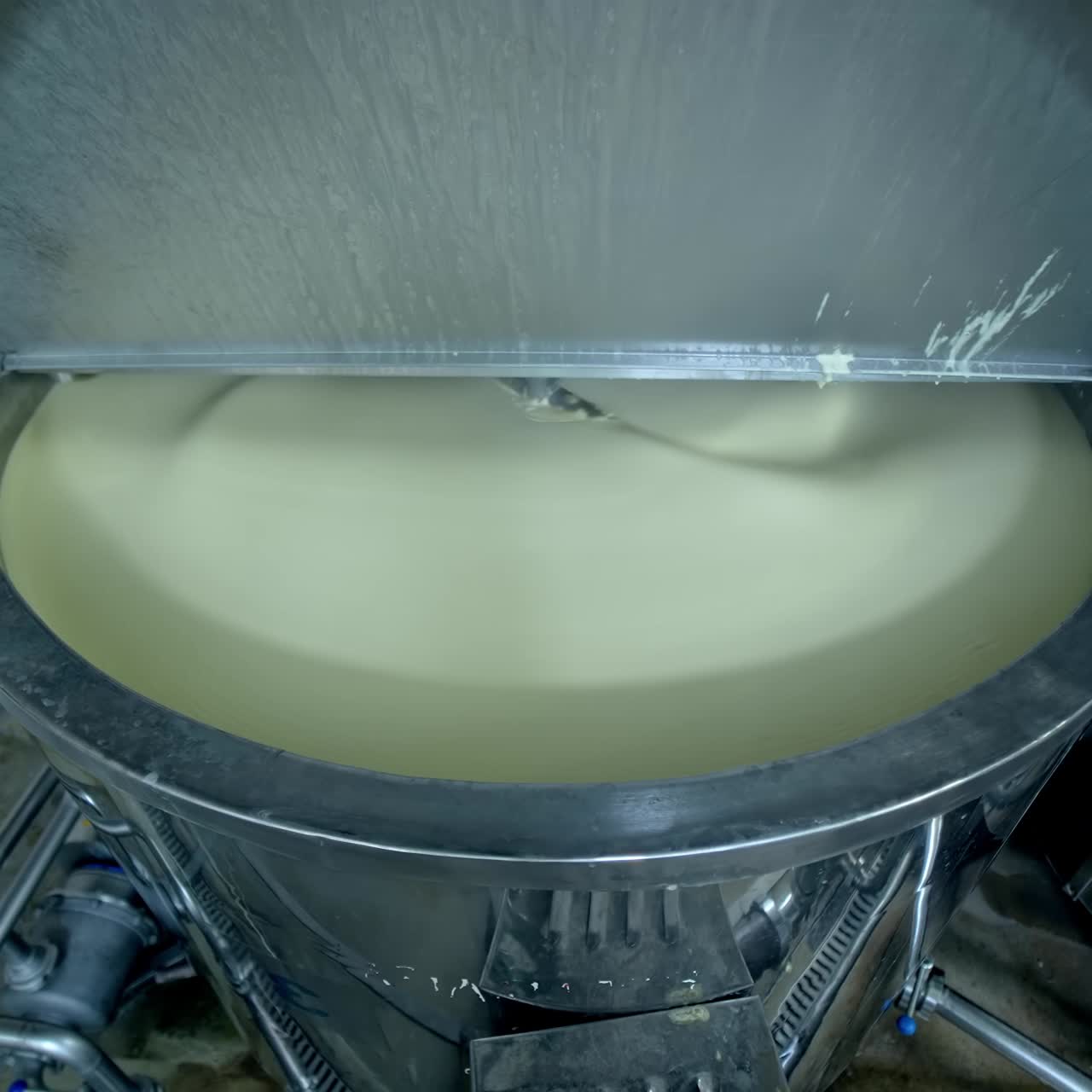 Big cistern with automatic mixing system inside. Beating the butter in automatic mixer tank. Butter production at milk factory close up