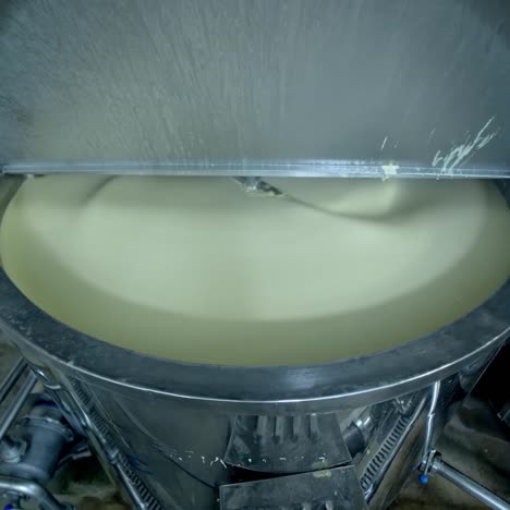 big cistern with automatic mixing system inside. beating the butter in automatic mixer tank. butter production at milk factory close up