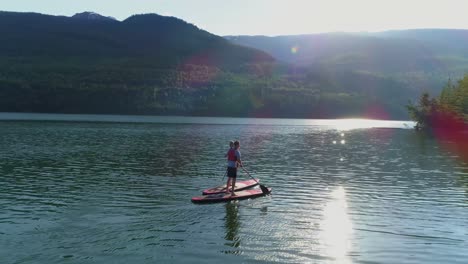 couple on stand up paddle board oaring in river 4k