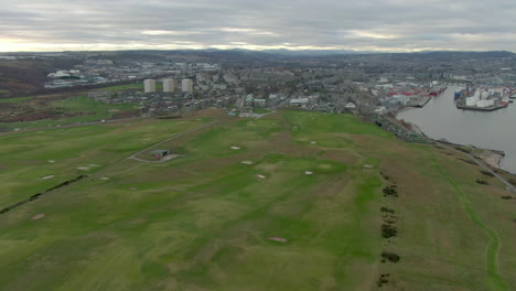 Vista-Aérea-Del-Campo-De-Golf-De-Aberdeen-Con-La-Ciudad-Al-Fondo-En-Un-Día-Nublado,-Aberdeenshire,-Escocia