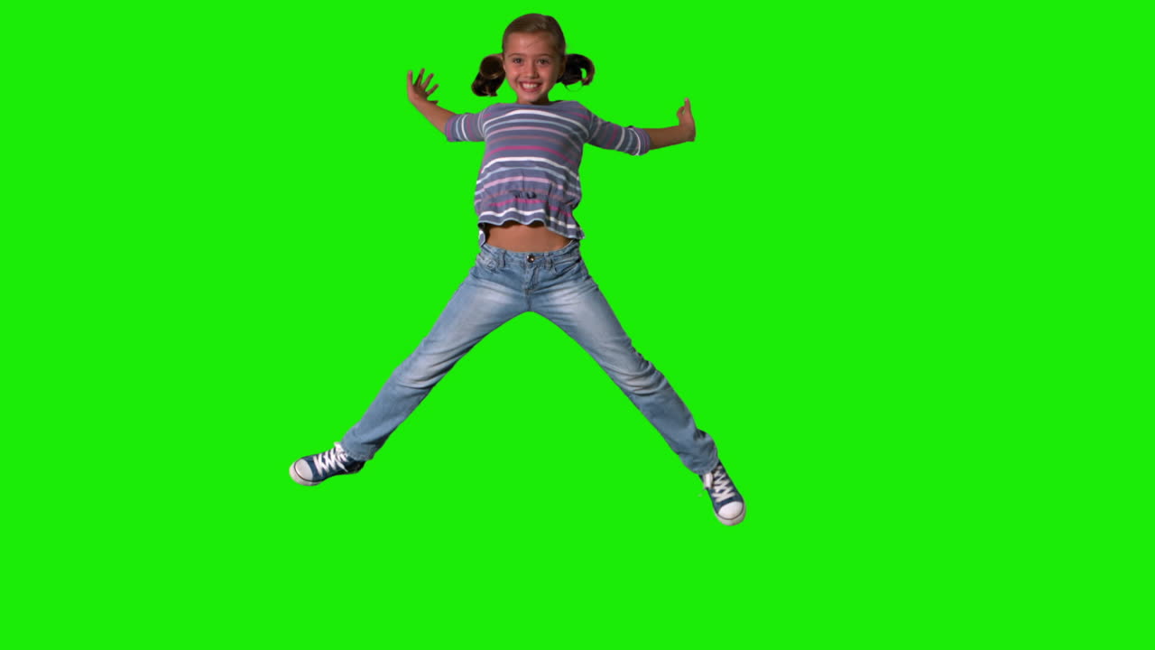 Smiling girl jumping up and down on green screen