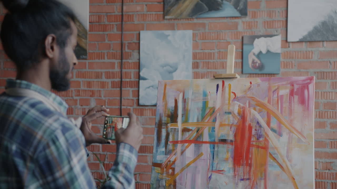 Artist taking a photo of a painting in a studio