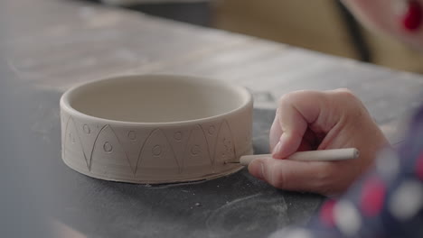 woman hands during painting on ceramic plates. potter workshop of making handcraft clay dishes. artist creates a beautiful pattern on earthenware in a pottery workshop. close-up slow motion