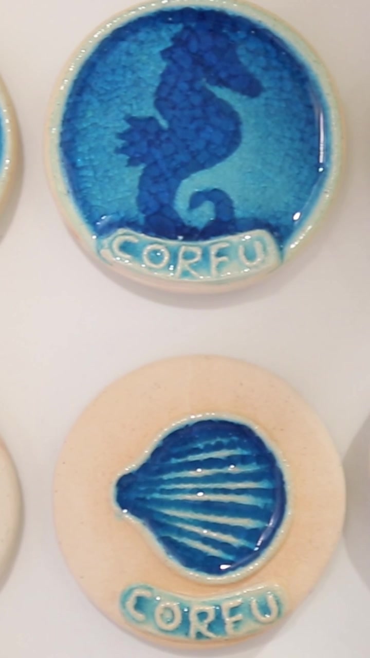Carrellata verticale di autentici magneti souvenir in ceramica greca fatti a mano raffiguranti vita marina in un negozio di souvenir a Corfù, Grecia
