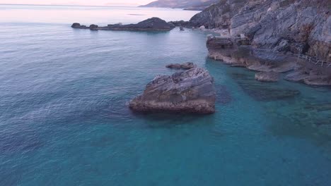 Aerial-orbiting-drone-shot-of-a-big-rock-in-the-crystal-clear-waters-of-the-sea-in-Greece