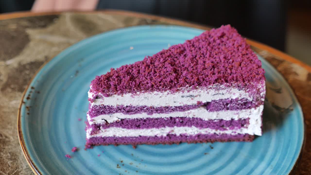 Et stykke lilla kake med hvit glasur og smuldretopp