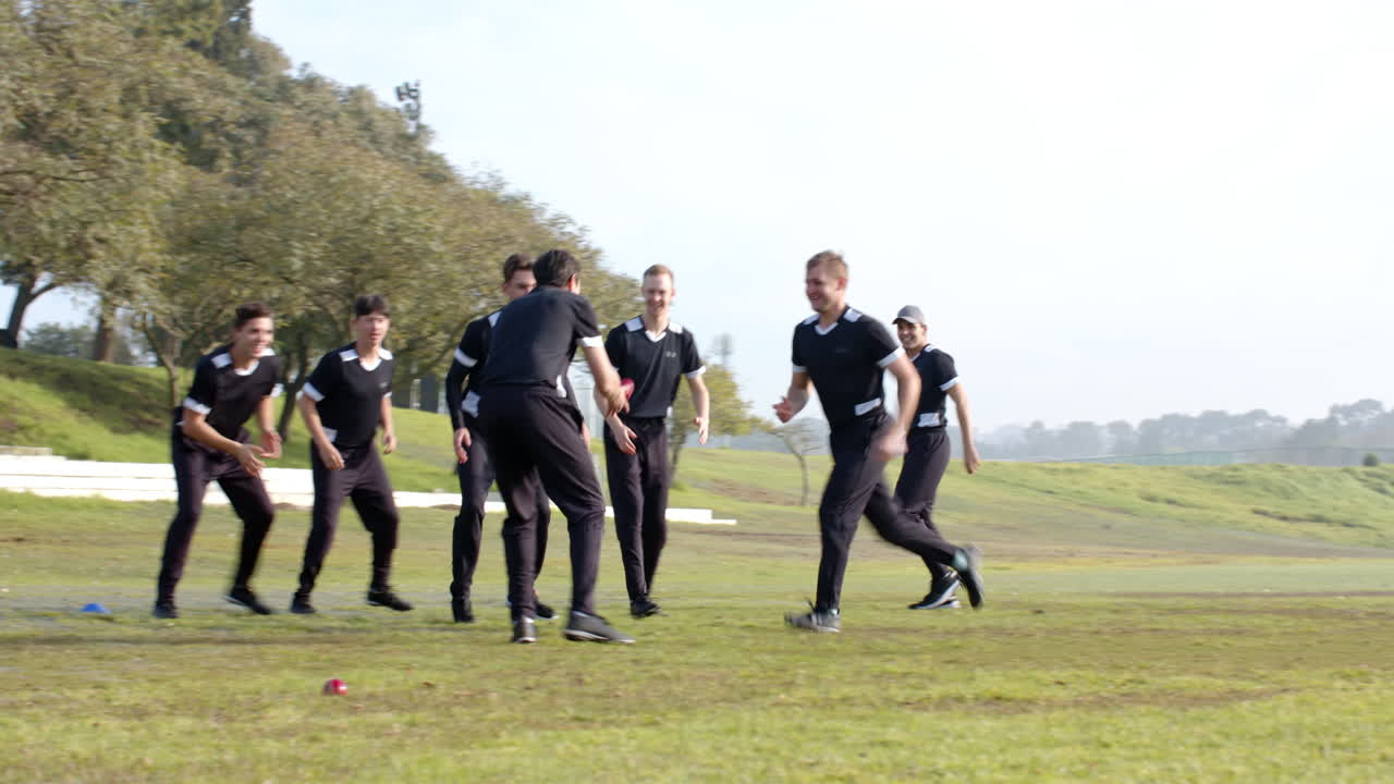Playing cricket on field, group of men in black uniforms practicing game
