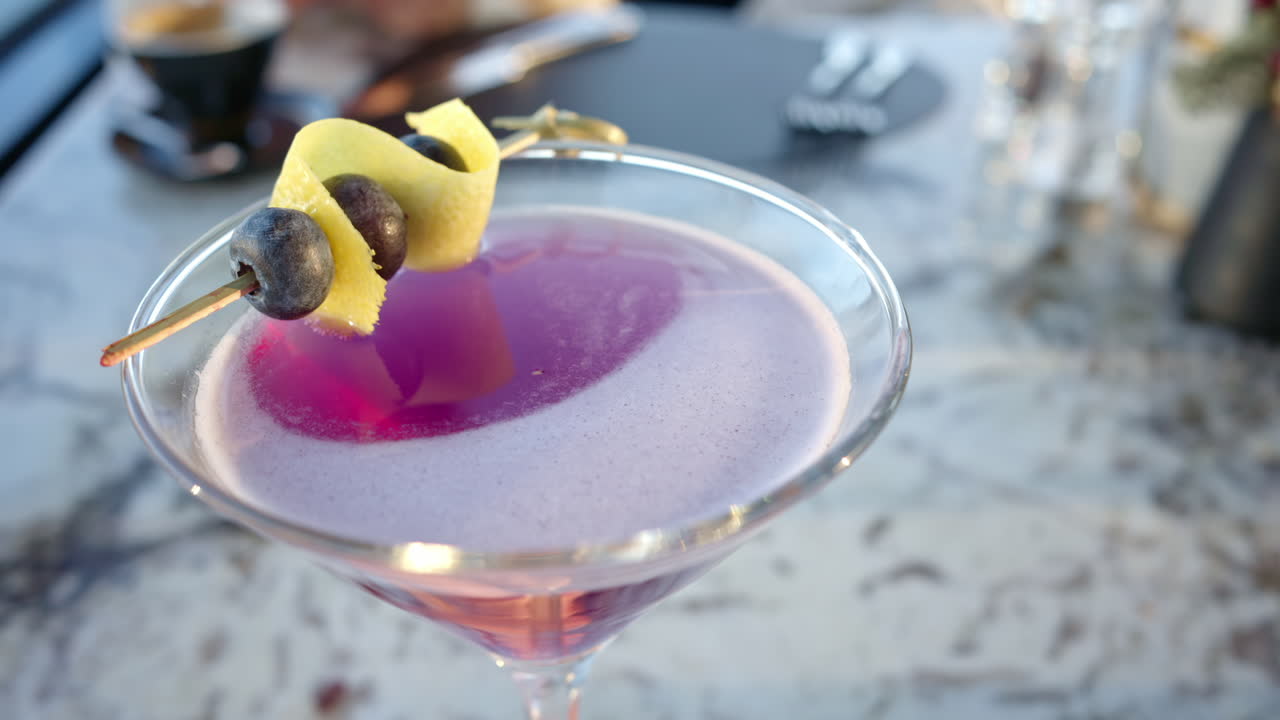 Pink red martini with blueberries on top close up