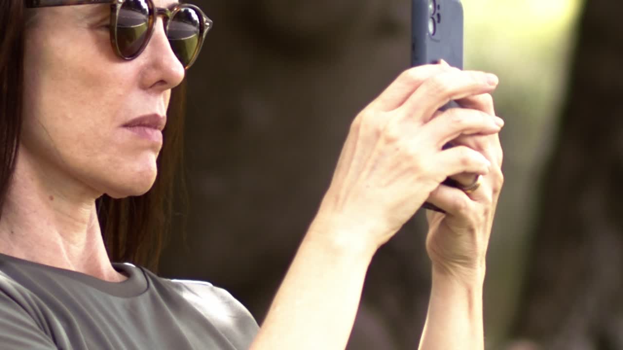 She stands focused on her phone, a blend of glamour and tech