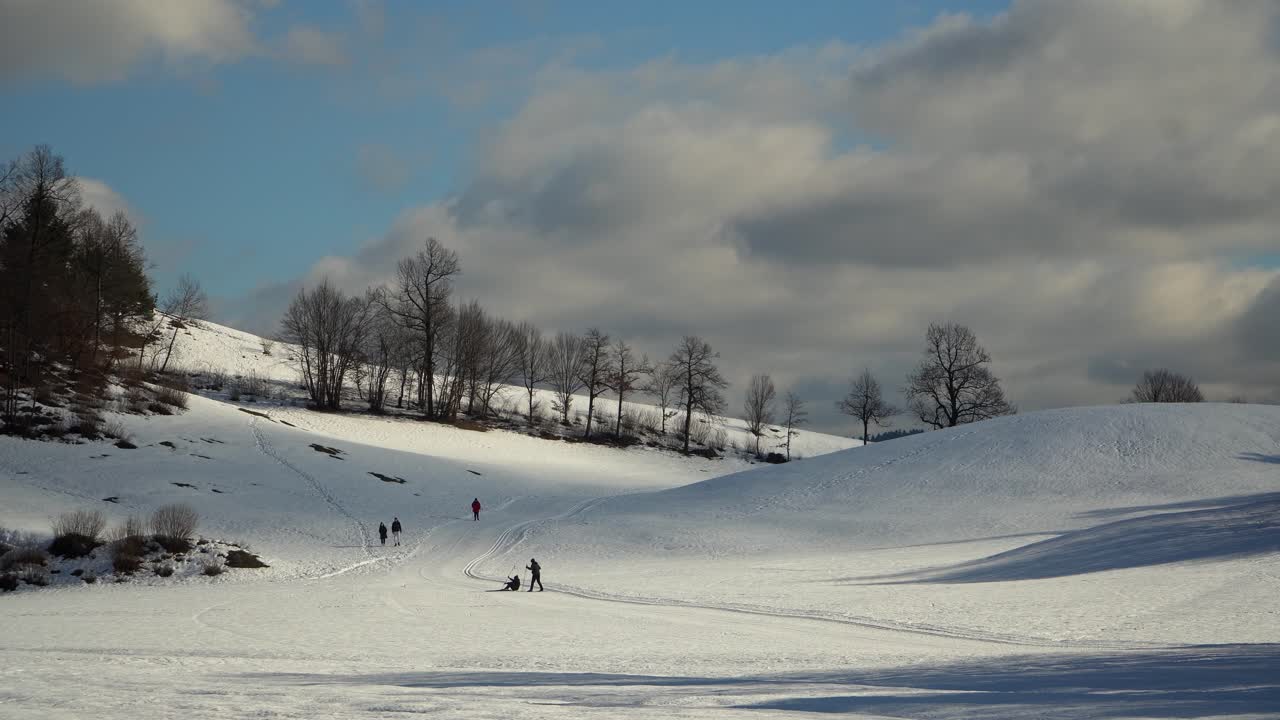 Vista di un paesaggio innevato con nuvole sullo sfondo e persone che si svagano