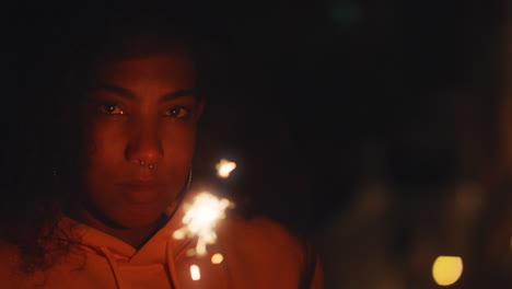 retrato de una joven afroamericana sosteniendo una bengala celebrando la víspera de año nuevo en la azotea por la noche