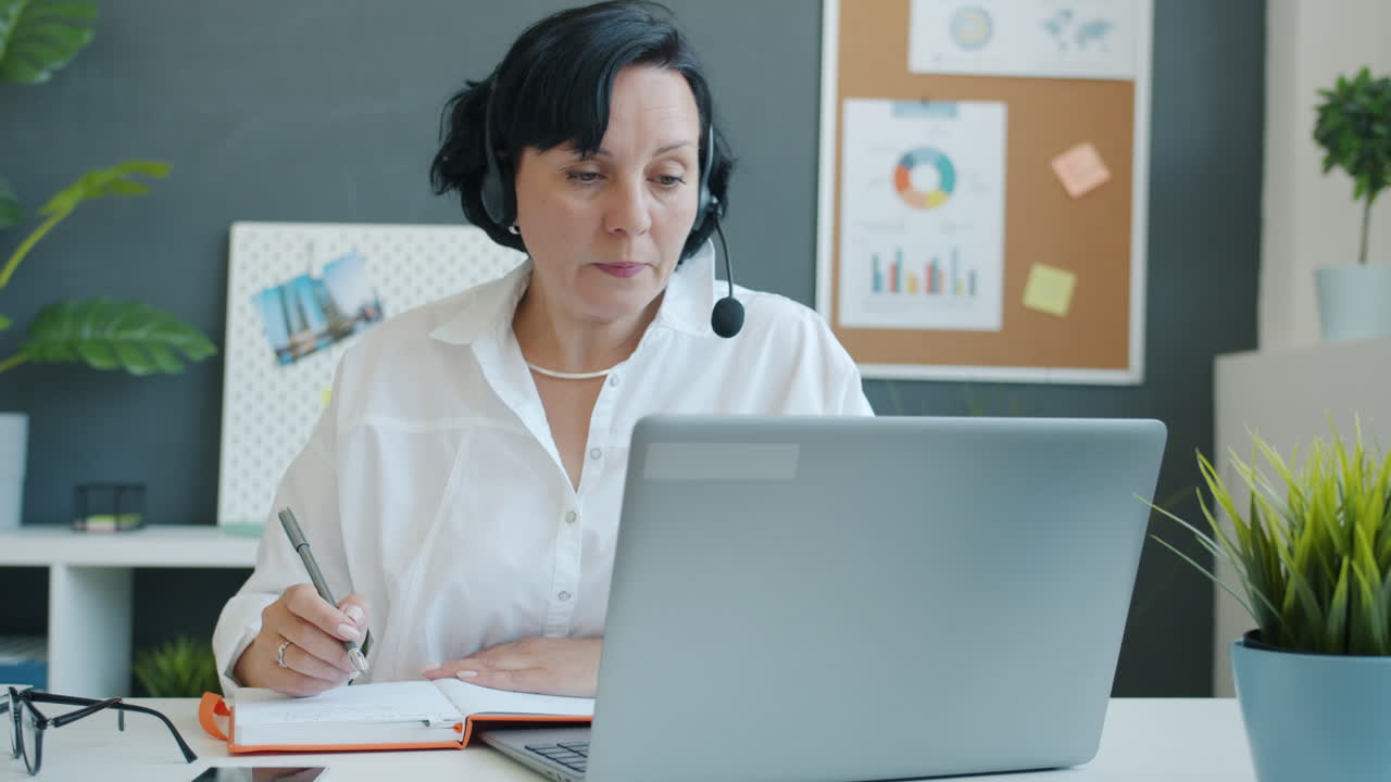 Businesswoman working on laptop and taking notes