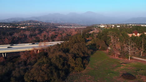 Mosca-Aérea-Por-Un-Puente-Al-Atardecer-En-Una-Ciudad-Suburbana