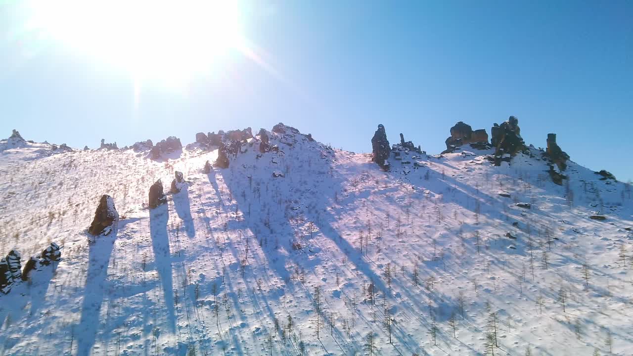 tiempo soleado, montaña nevada y rocas en él, volando un dron
