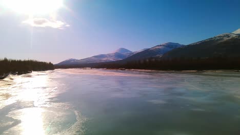 flying-over-a-frozen-river-and-a-gray-forest-in-sunny-Yakutia-at-a-bird's-eye-view