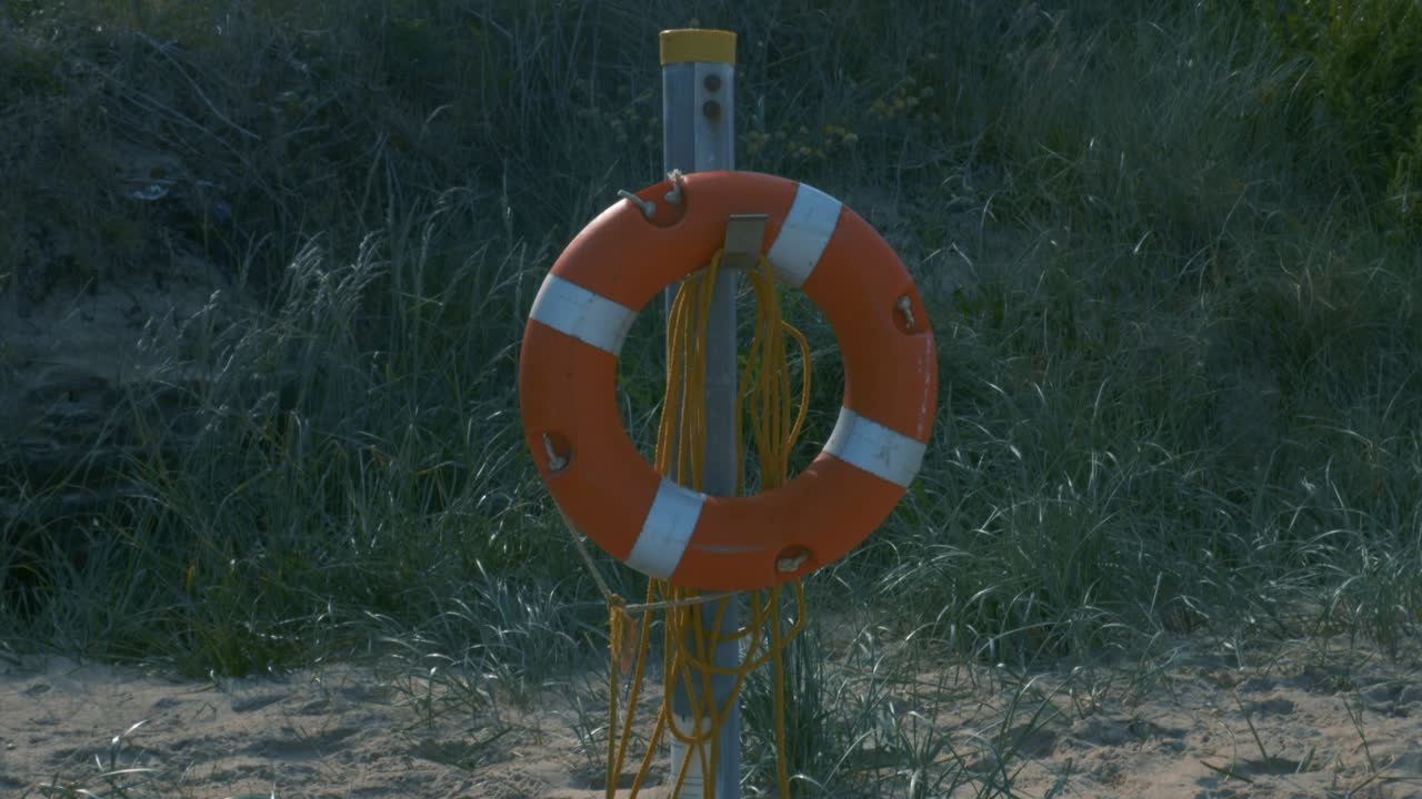 Lifeguard Ring Hangs On A Metal Post In Brittas Bay Beach In Ireland During Summer.  - pan up