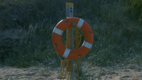 lifeguard ring hangs on a metal post in brittas bay beach in ireland during summer.  - pan up