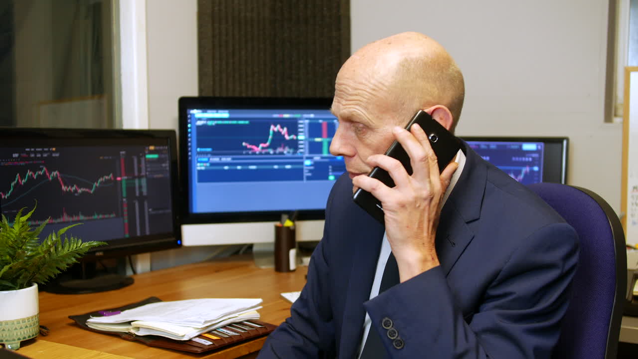 Un uomo d'affari maturo, broker di borsa, riceve e risponde a una telefonata nel suo ufficio di trading