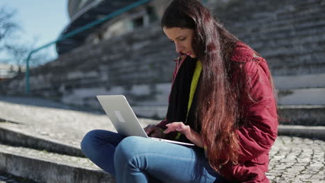 Konzentrierte-Reife-Frau-Mit-Langen-Dunklen-Haaren,-Die-Im-Freien-Einen-Laptop-Benutzt