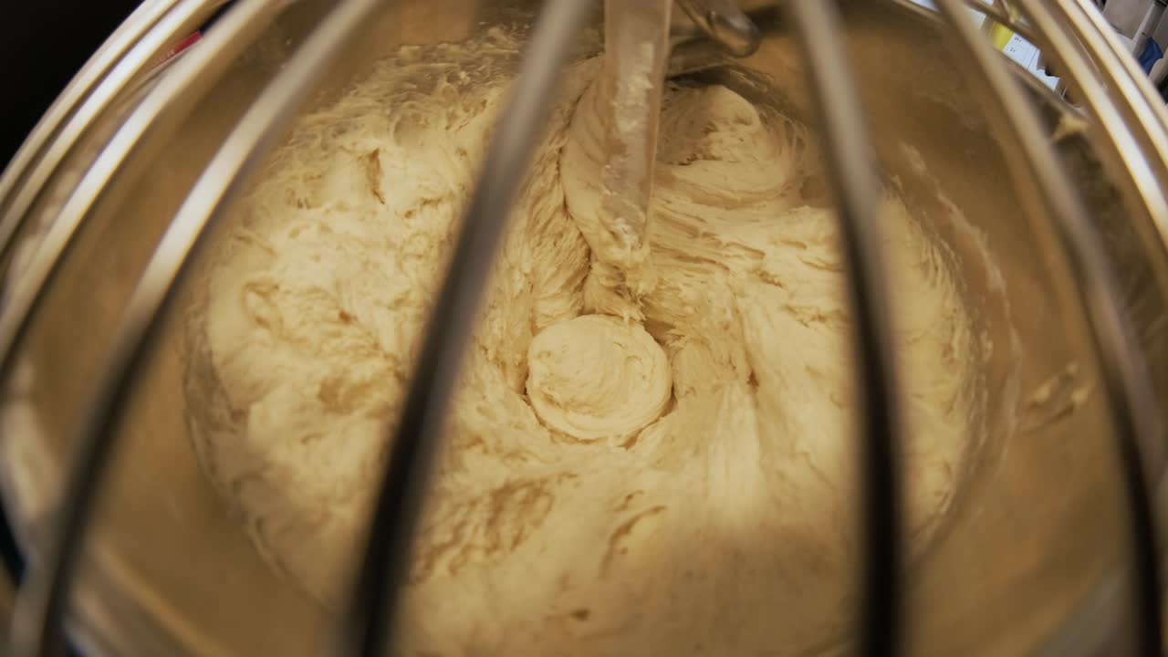 Close-up of dough mixing in a professional kneader machine in kitchen of bakery or at the manufacturing. Stock footage. Dough making process