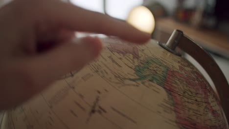 white hand stopping a globe from spinning and pointing to canada