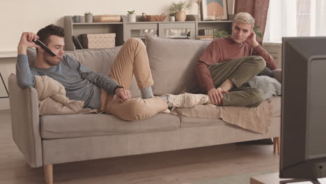 couple resting on sofa and watching tv