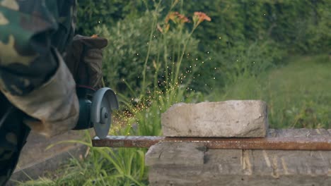 slow motion man in camouflage cuts metal with circular saw