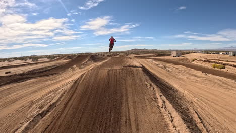 motorcycles racing on an off-road track with high jumps and stunts - first person view drone