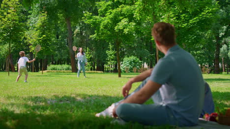 Padre-Joven-Viendo-El-Juego-De-Bádminton-Vista-Borrosa.-Actividad-Al-Aire-Libre-En-El-Parque.