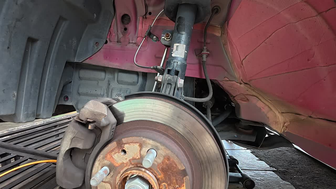 The car's exposed disk brake is ready for servicing at the workshop. The wheel has been removed for maintenance, ensuring optimal braking performance and safety.