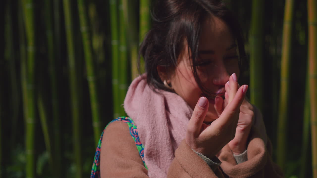 mujer morena con la mano en la boca mientras se ríe al aire libre