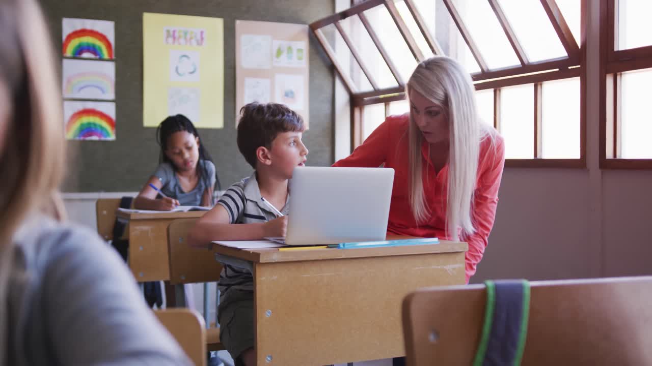 maestra y niño usando computadora portátil en clase en la escuela