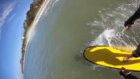 surfer surfing on yellow longboard on tropical beach in vietnam, pov vertical slow motion