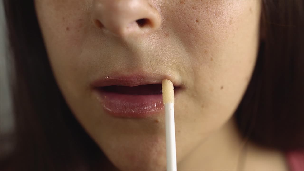 입술에 립글로스를 바르고 립글로스를 바르는 젊은 여성