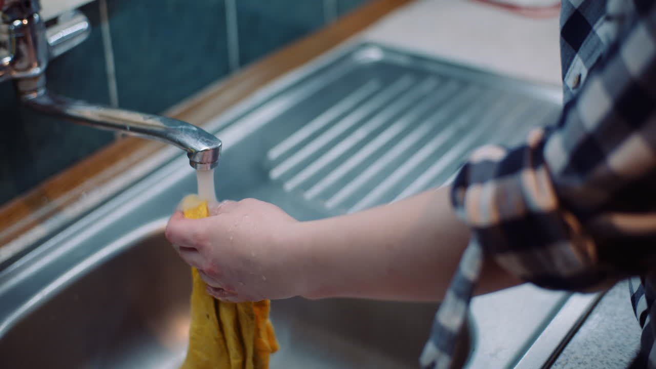 cerca de una mujer lavando una servilleta con agua en el fregadero de la cocina