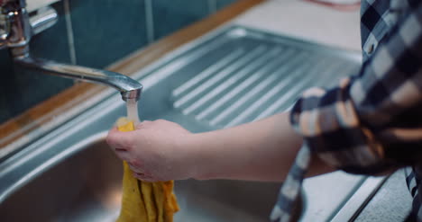 close up of woman washing napkin with water at sink in kitchen