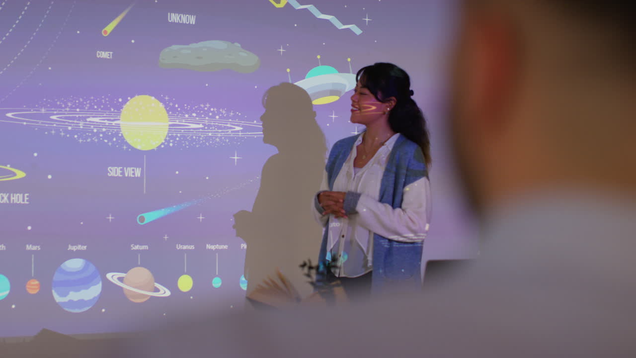 maestra dando lección de astronomía en la escuela de pie en la parte delantera de la clase con la proyección del sistema solar 4